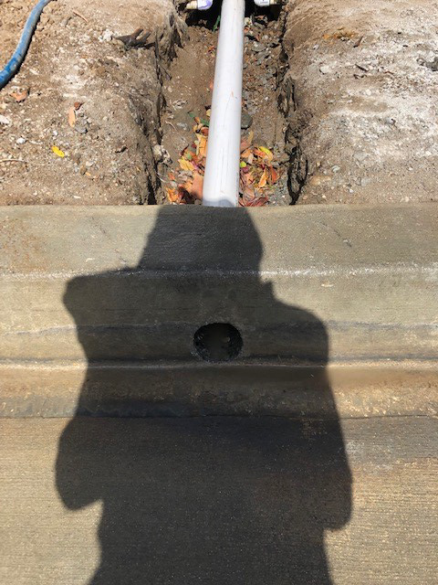 Core drilled in curb for french drain drainage