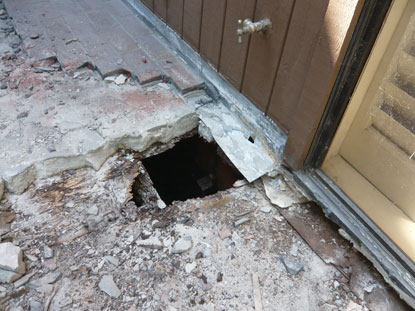 Substandard courtyard deck flashing installation above sloping cement and to vertical siding. Setting flashing to plywood substrate and behind vertical siding is required by code